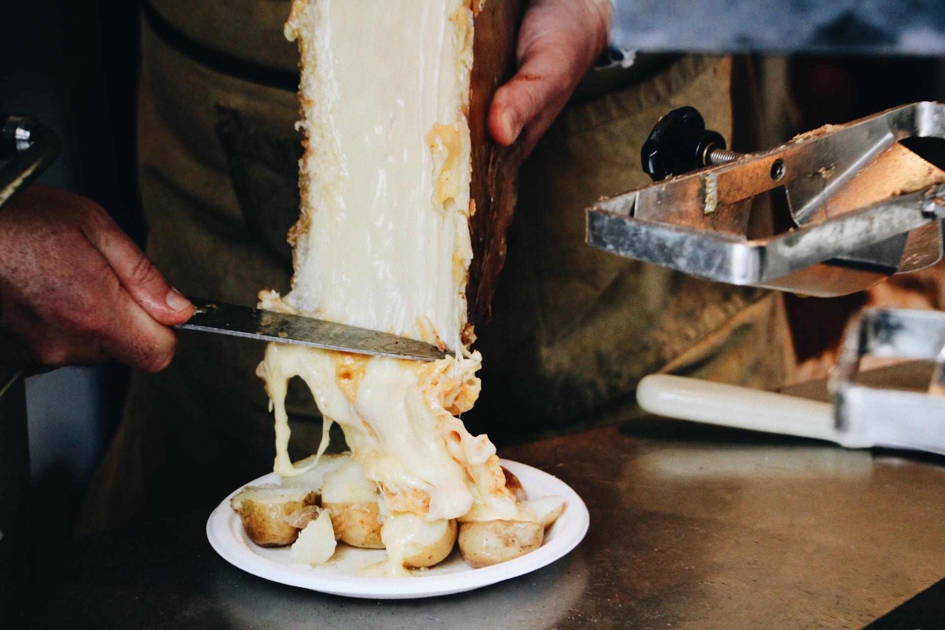 Waiter carves off raclette cheese to eat with potatoes at French ski resort