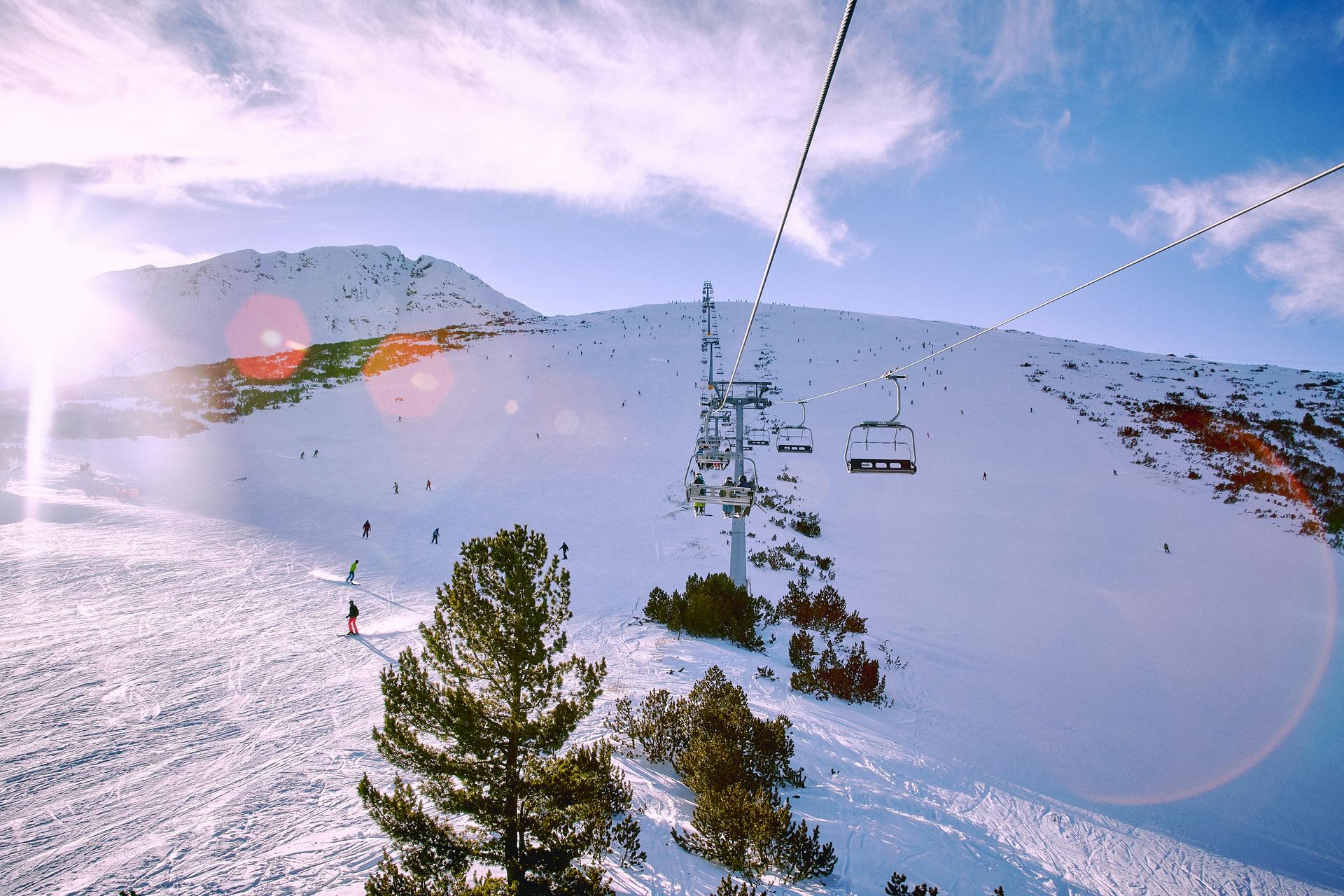 Chairlift transporting skiiers to top of mountain with ski slope below