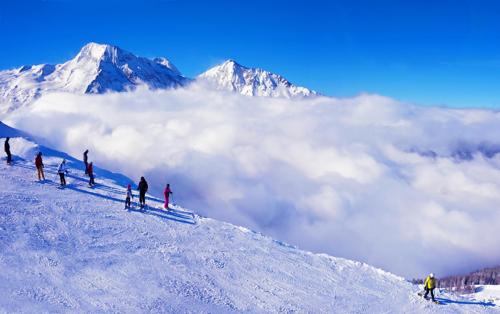 Skiers enjoying view of rolling clouds above French Alps